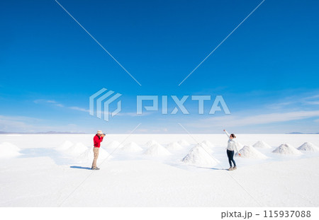 Tourists taking photos at sault banks on background of sunshine Salar de Uyuni Tourists taking photos at sault banks on background of sunshine Salar de Uyuni 115937088