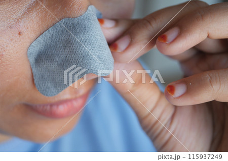 A woman uses a pore strip in her skincare routine to maintain appearance and promote skin health 115937249