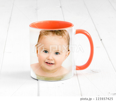 Small orange cup with bright orange handle and a printed face of a baby Small orange cup with bright orange handle and a printed face of a baby 115937425