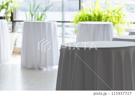 Round tables for the buffet are covered with white tablecloths Round tables for the buffet are covered with white tablecloths 115937727
