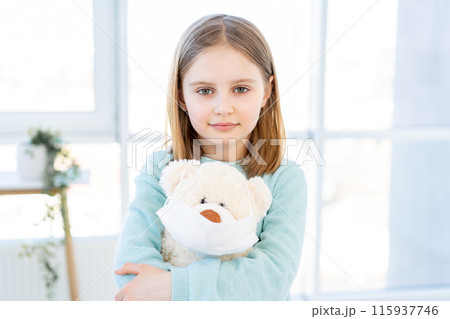 Cute little girl holding teddy bear in mask Cute little girl holding teddy bear in mask 115937746