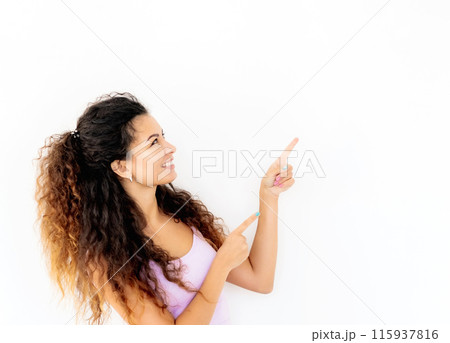 Cheerful young girl standing sideways and pointing up 115937816
