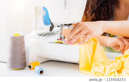 Close up view of female hands working on sewing machine Close up view of female hands working on sewing machine 115938253