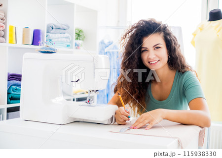Happy tailor measuring cloth in light workroom 115938330