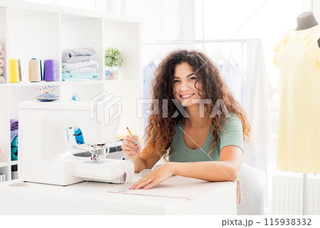 Happy tailor measuring cloth in light workroom Happy tailor measuring cloth in light workroom 115938332