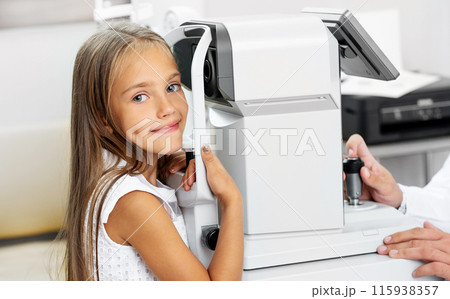 Little blond girl with a special modern diagnostics device in the ophthalmologic clinic 115938357