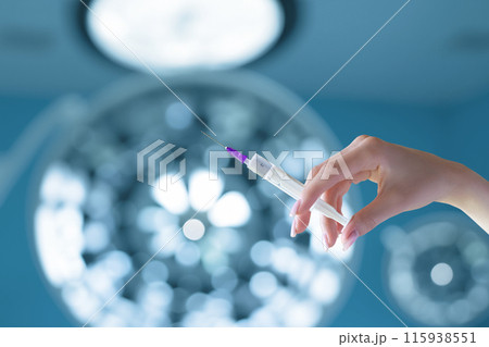 A hand holds a syringe of medicine . 115938551