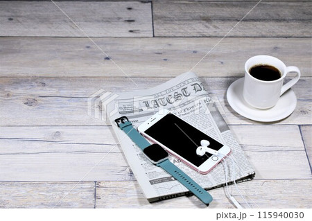 テーブルの上のコーヒーとスマホと英字新聞 115940030