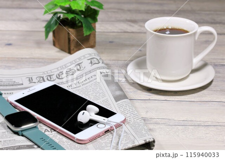 テーブルの上のコーヒーとスマホと英字新聞 115940033