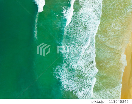 Aerial view sandy beach and waves crashing on sandy shore, Beautiful tropical sea surface background Aerial view sandy beach and waves crashing on sandy shore, Beautiful tropical sea surface background 115940843