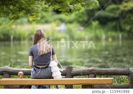 一人で公園のベンチに座る孤独な若い女性のイメージ 115941998