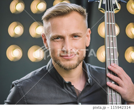 Close-up of smiling musician holding guitar with stage lights 115942314