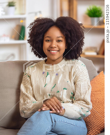 Smiling Young Woman Relaxing on Cozy Sofa in Bright Living Room 115942316