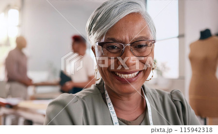 Cheerful mature woman with glasses and measuring tape smiles warmly in a bright workspace 115942318