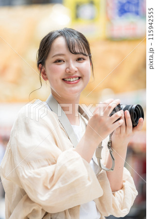 都会の繁華街を観光しながら趣味の一眼レフで写真を撮るカメラ女子｜カメラマンイメージ 115942555