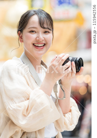 都会の繁華街を観光しながら趣味の一眼レフで写真を撮るカメラ女子｜カメラマンイメージ 115942556