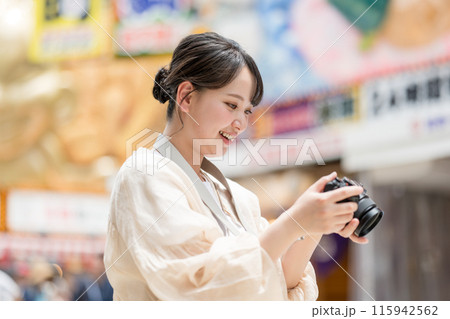 都会の繁華街を観光しながら趣味の一眼レフで写真を撮るカメラ女子|カメラマンイメージ 都会の繁華街を観光しながら趣味の一眼レフで写真を撮るカメラ女子|カメラマンイメージ 115942562