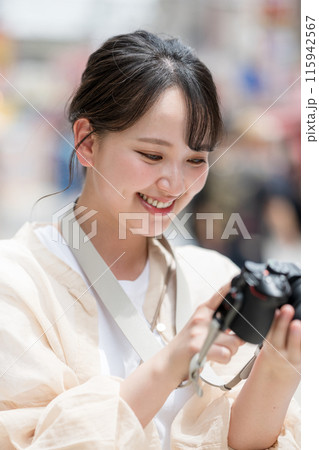 都会の繁華街を観光しながら趣味の一眼レフで写真を撮るカメラ女子｜カメラマンイメージ 115942567