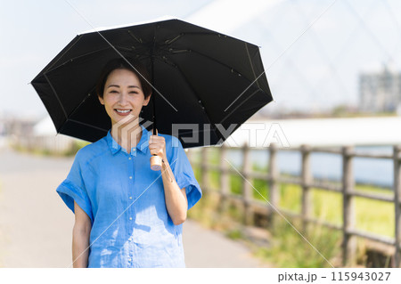 日傘をさして散歩する若い女性　ライフスタイルイメージ 115943027