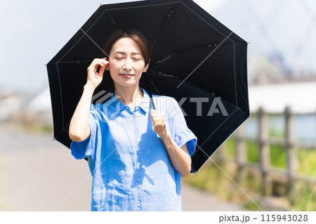 日傘をさして散歩する若い女性　ライフスタイルイメージ 115943028