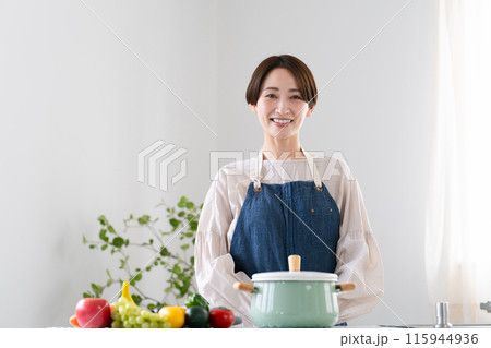 エプロン姿で料理する若い女性 ライフスタイルイメージ エプロン姿で料理する若い女性 ライフスタイルイメージ 115944936