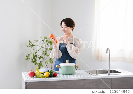 エプロン姿で料理する若い女性　ライフスタイルイメージ 115944946