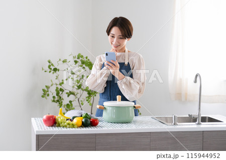 エプロン姿で料理する若い女性 ライフスタイルイメージ エプロン姿で料理する若い女性 ライフスタイルイメージ 115944952