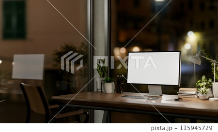 Contemporary private office at night features a computer with a white-screen mockup and a dim light. Contemporary private office at night features a computer with a white-screen mockup and a dim light. 115945729