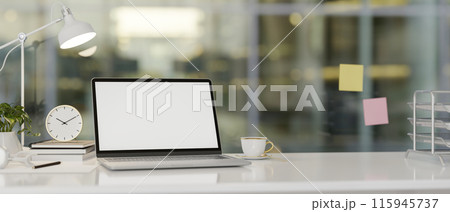 Modern office features a laptop computer with a white-screen mockup and accessories on a white desk. 115945737