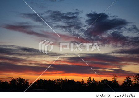 Sun setting casting a golden orange hue upon the clouds 115945863