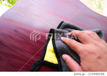 Human hand wiping to clean an acoustic guitar with a cloth for polishing 115946399