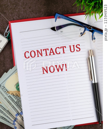 Copy space. Contact us now words written in a red business notebook in a composition with money and glasses Copy space. Contact us now words written in a red business notebook in a composition with money and glasses 115949523