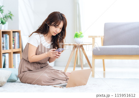 リビングでパソコンを見る若い女性 115951612