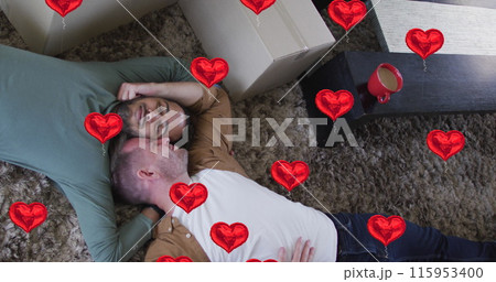 Image of heart icons over diverse gay couple lying 115953400