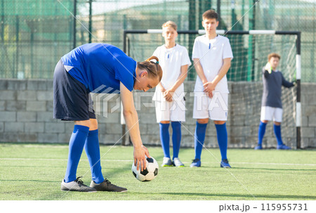 Football player putting ball for kick 115955731