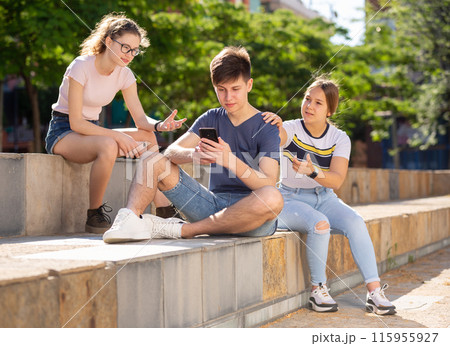 Teenager with smartphone not paying attention to girlfriends outdoor 115955927