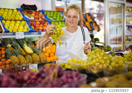 Teen shopper chooses grape at grocery store Teen shopper chooses grape at grocery store 115955937