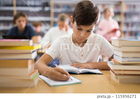 Ten-year-old schoolboy takes notes in an exercise book of the necessary material Ten-year-old schoolboy takes notes in an exercise book of the necessary material 115956271