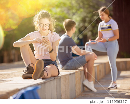 Teen girl is passionate about playing on smartphone Teen girl is passionate about playing on smartphone 115956337