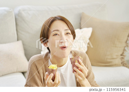 自宅で焼き芋を食べる女性 115956341