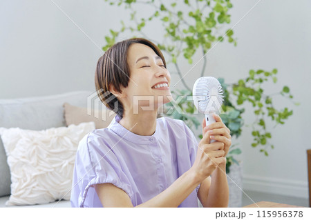 リビングで携帯扇風機を使う女性 リビングで携帯扇風機を使う女性 115956378