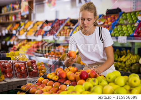 Young woman purchaser choosing apples in grocery 115956699