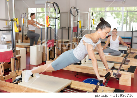 Young girl doing full body exercises lying on reformer device Young girl doing full body exercises lying on reformer device 115956710