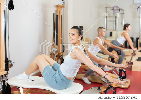 Sportive young girl training her back and shoulders on exercise machine Sportive young girl training her back and shoulders on exercise machine 115957243