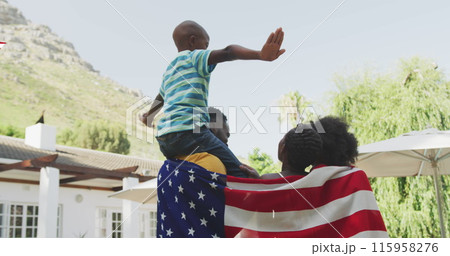 Black young man lifts child on shoulders, both in casual wear 115958276
