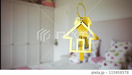 A golden house-shaped keychain hanging in focus with blurred bedroom background A golden house-shaped keychain hanging in focus with blurred bedroom background 115958578