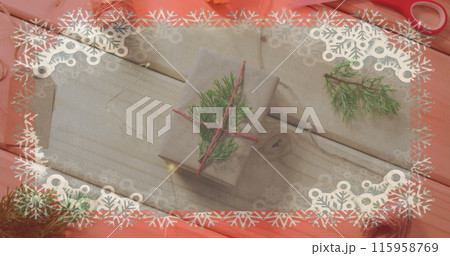 Two gifts wrapped in cloth lie on pink surface, adorned with pine twigs 115958769