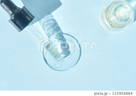 Serum gel texture swatch. Transparent drop golden sparkles. Blue background Serum gel texture swatch. Transparent drop golden sparkles. Blue background 115958864