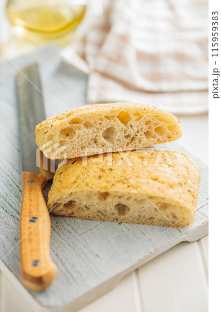 Italian ciabatta bread on cutting board on white table. Italian ciabatta bread on cutting board on white table. 115959383