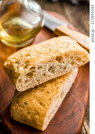 Italian ciabatta bread on cutting board on wooden table. 115959393